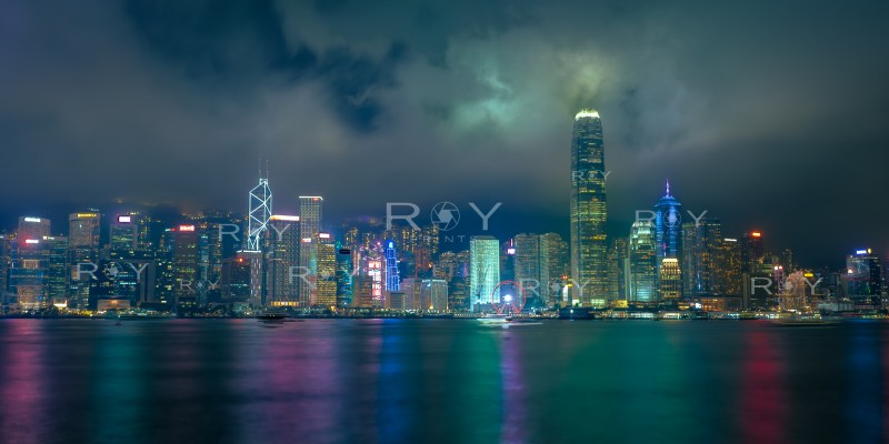 Hong Kong skyline lit up at night with mist and colorful water reflections.